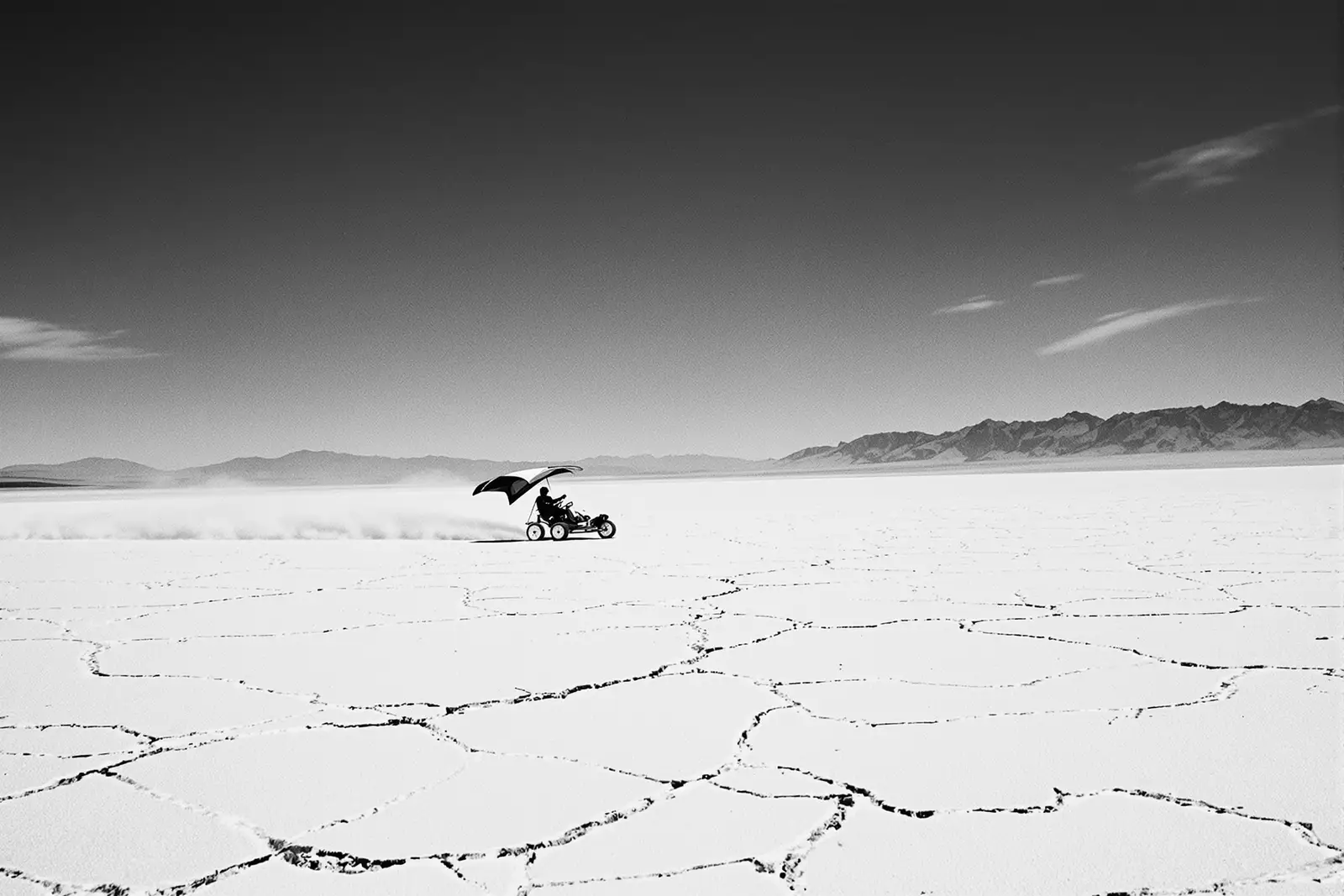 Kitebuggy cruzando un salar a toda velocidad, con un foil de tracción y montañas al fondo