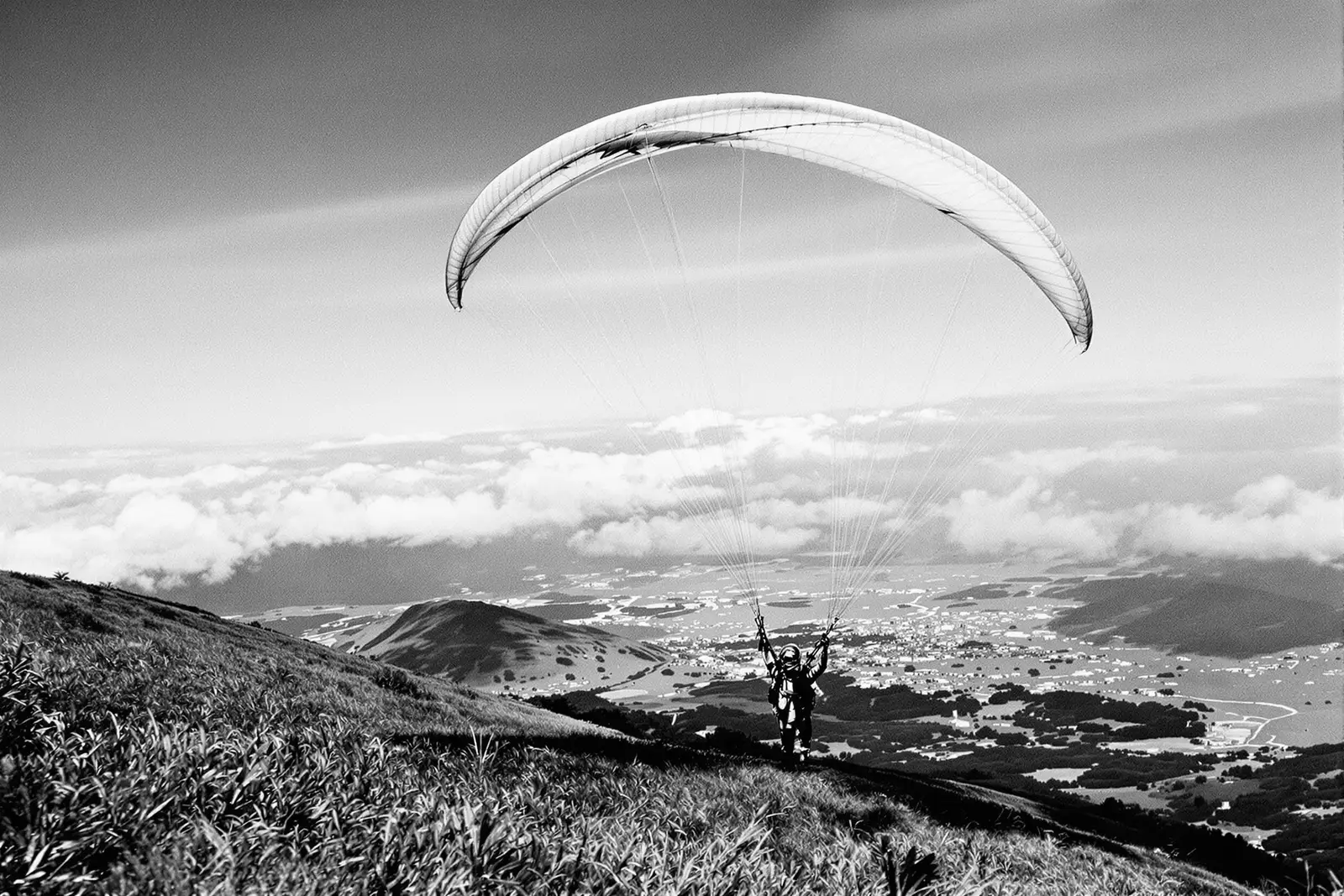 Piloto de parapente despegando desde una ladera con el ala inflada sobre su cabeza