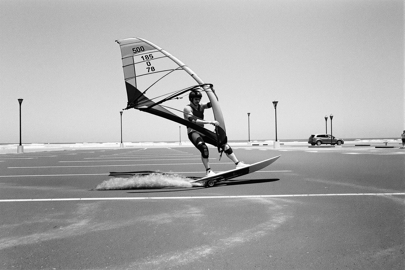 Windskater deslizando sobre un estacionamiento vacío junto al mar
